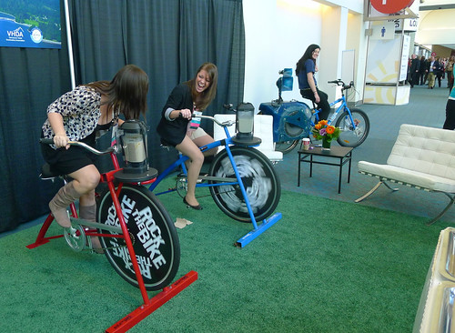 women in dress clothes generate power by pedaling bikes at a conference
