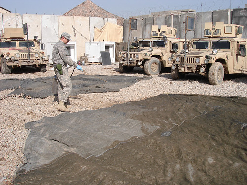 At a remote patrol base in Iraq, ARS scientist and U.S. Army entomologist Seth Britch applies a pesticide treatment to camouflage netting and shade cloth that will be suspended over outdoor eating and cooking areas and areas between dormitories. This treatment reduces populations of biting flies and mosquitoes by transferring lethal doses to the insects when they rest on the camouflage material.