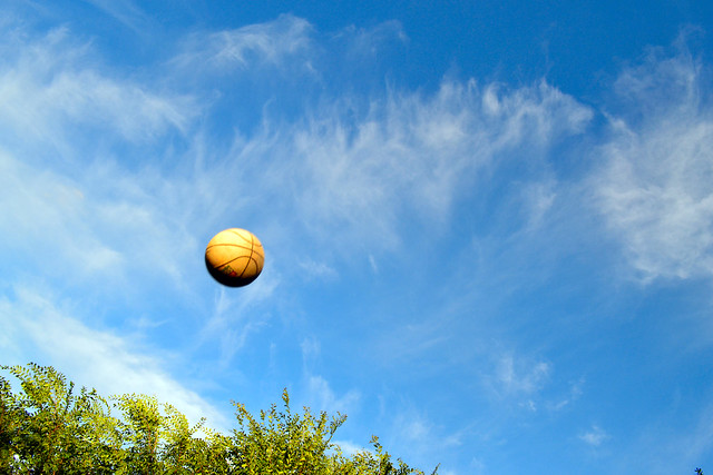 A photo that freezes or isolates the motion of an object - Basketball against the late afternoon sky