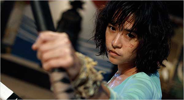 Zen, a young Asian woman, holds a bow staff of some sort and looks ready to fight