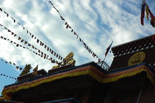 The top story of Tharlam Monastery as seen from the courtyard at dusk, sky, prayer flags, deer and dharma wheel, Sakya Lamdre, Boudha, Kathmandu, Nepal by Wonderlane