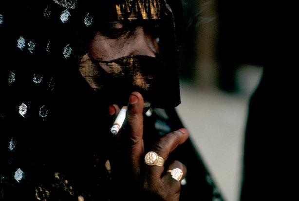 veiled woman in Dubai lights a cigarette