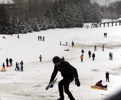 Sledder with a board climbing back up the big hill at Gas Works Park, arches, snow boater, people, Seattle, Washington, USA by Wonderlane