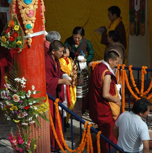 Sakya family members share a moment in the blessing line, Tibetan Buddhist monks, behind a brightly painted flower covered column, Long Life Blessing, Tharlam Monastery stage, Boudha, Kathmandu, Nepal by Wonderlane