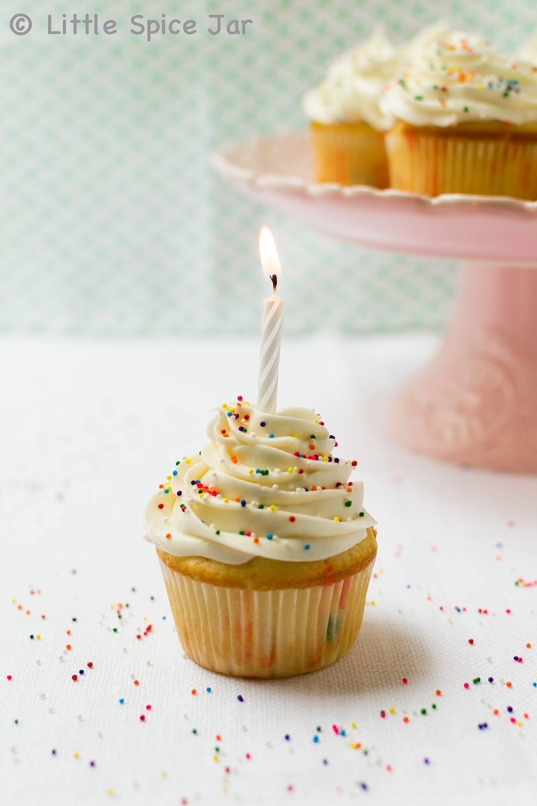 cupcake with frosting and sprinkled with lit candle