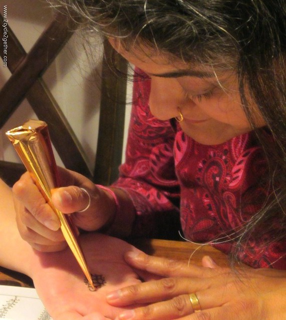 Sujatha applying mehndi design on Sheila's palm