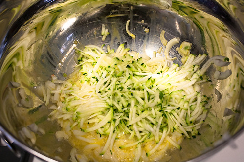 Shredded zucchini, egg, onions, and garlic in a metal bowl