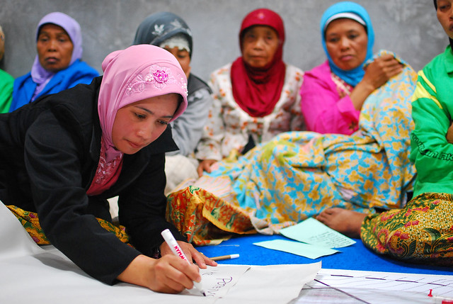 Women at a community meeting discuss the reconstruction of their village