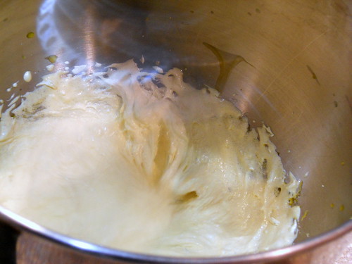 Mixing bowl showing egg yolks, salt, half of sugar and herbs after mixing. It is white and thick looking with traces of egg yolk still showing. Volume has doubled.