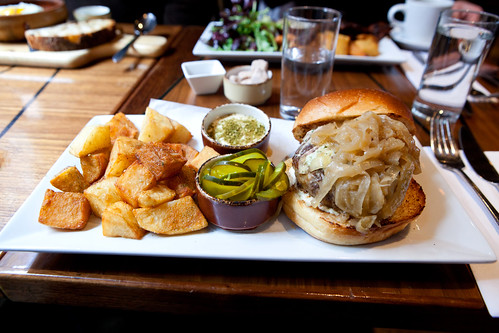 Lamb burger Stuffed with Herbed Goat Cheese, served with Caramelized Onions, Brioche Bun, Patatas Bravas
