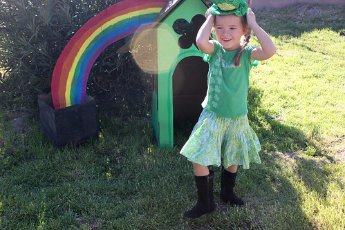 smiling child standing in front of a cardboard leprechaun house 