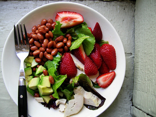 green salad with chicken, red beans, avocado, and strawberries