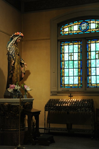 Statue of Mary, stained glass windows with cross, votive candles, flowers, capital, chapel, St. James Cathedral, First Hill, Seattle, Washington, USA by Wonderlane