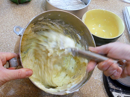 Folding whites and egg yolks and flour mixture together in a metal mixing bowl.