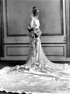 a black and white photo of a bride in a long white dress with a train