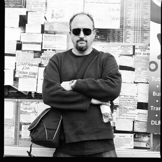 a black and white photo of Louis CK against a wall