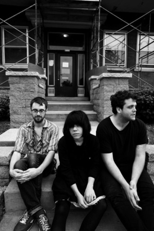 the members of screaming females sitting on steps looking pensively into the camera, as one member gazes into the distance