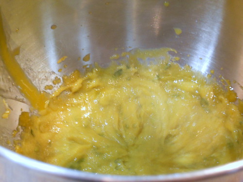 Shot of interior of metal mixing bowl showing mixed up egg yolks, salt, herbs and half the sugar.