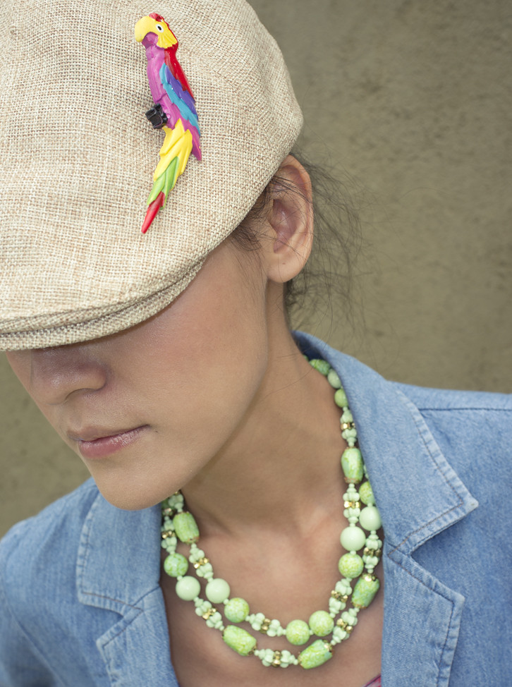 The accessories say it all. Polly's Got A Cracker brooch pinned on a hat, and bright green 1960s beads.  