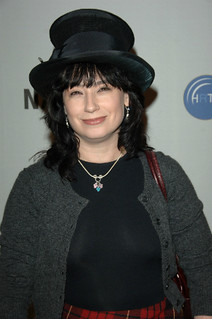 a photo of amy sherman-palladino smirking and wearing an oversized black velvet hat
