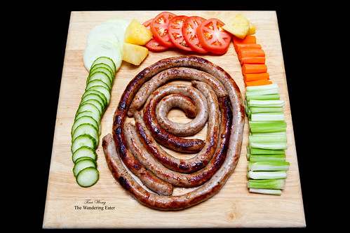 A large board of Pat LaFrieda's Grandpa's Provolone Cheese Sausage with crudite and cubes of fresh pineapples