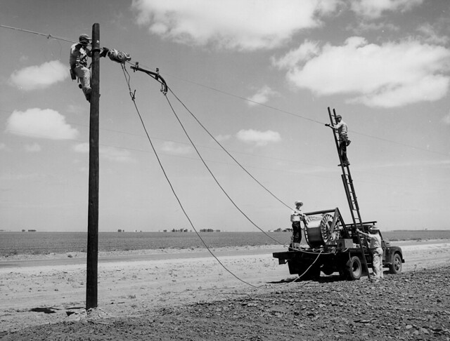 Rural Electrification Administration workers erect telephone lines in rural areas.