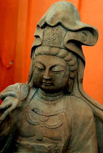 Asian Bodhisattva, holding a leaf, robe and jewelry, concrete, orange background, Lake City Way, Seattle, Washington, USA by Wonderlane