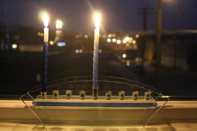 Menorah on the first night of Hanukkah and lights out the window