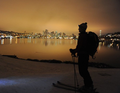 On record snow, night skier with pack and head light, city reflected in Lake Union, Space Needle, from the top of the hill, Gas Works Park, Wallingford, Seattle, Washington, USA by Wonderlane