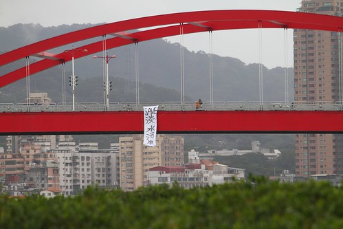 反對新建淡北快速道路，環團在關渡大橋垂下七公尺長「Save淡水河岸」的巨型抗議布條照片。綠色公民行動聯盟提供。