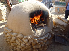 9.用廢棄輪胎及當地沙土石塊做成的稻草泥磚爐，正忙碌於烘烤pizza。 陳婉寧攝