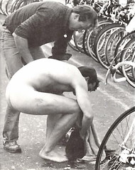 Naked guy crouched by his bike in transition