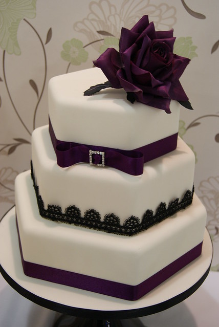 Stacked hexagon shaped cakes trimmed with deep purple ribbon and black lace