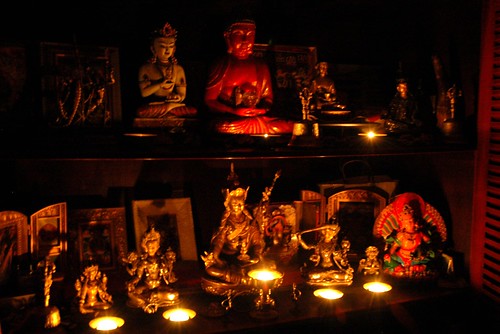 Tibetan Buddhist shrine with votive candle offerings, Buddha, Bodhisattvas, yidams, bells, statues, night, San Mateo, California, USA by Wonderlane