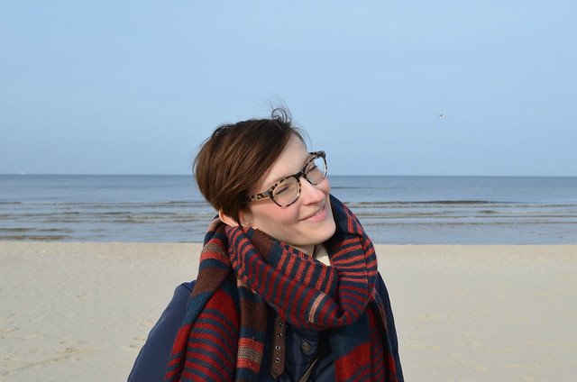 Świnoujście beach Poland_Kate bundled in down coat and Warby Parker Preston glasses in pearled tortoise_closeup