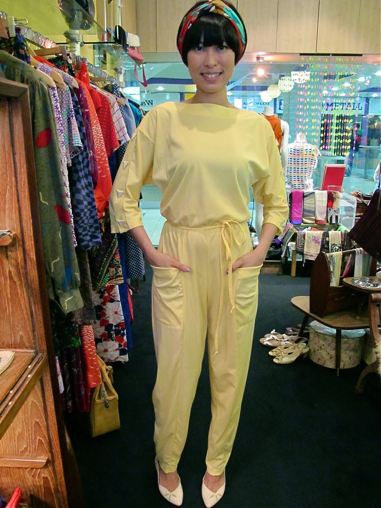 X-Wen wears a 1970s yellow jumpsuit with big pockets (on her body!), a French silk scarf (on her head!) and 1980s leaf-print pumps (on her feet!).
