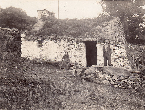 Old couple and a tumbledown whitewashed thatched bothy. Unidentified location. Scotland?
