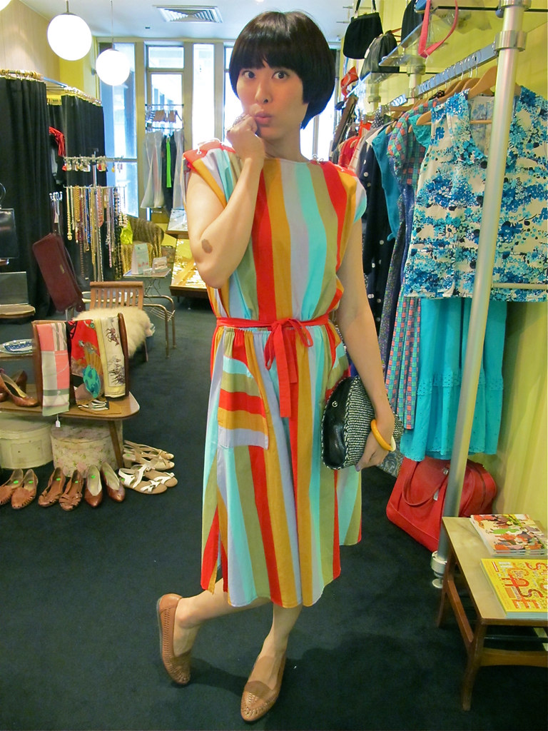 X-Wen looks happy in this brightly-coloured candy striped dress, worn with a 1980s orange and white plastic bangle, 1980s brown leather sandals and a 1970s woven clutch bag.