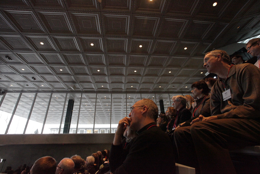 Alumni enjoying the Rem Koolhaas lecture in the Abby and Howard Milstein Auditorium. The view shows the auditorium ceiling and University Avenue cantilever. 