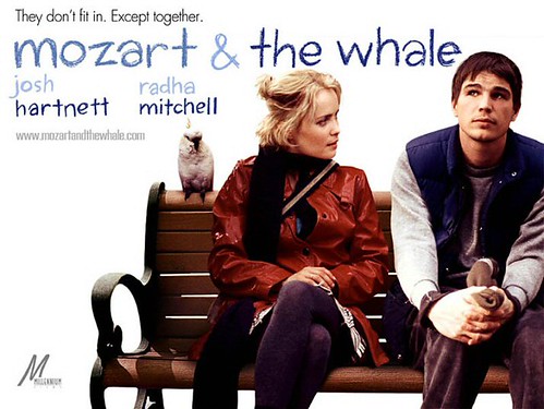 A poster for Mozart and the Whale: Josh Harnett and Radha Mitchell sit on a park bench together. 