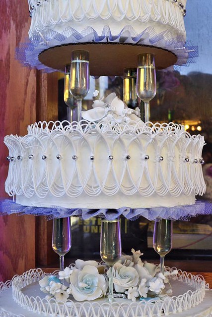 The layers of a wedding cake supported by miniature champagne glasses in a