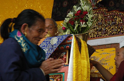 Monk attending HH Dagchen Rinpoche overseeing the long life initation from his throne, pleased Tibetan woman with her hands the prayer mudra happy with the blessing, two monks, Sakya Lamdre, Tharlam Monastery stage, Boudha, Kathmandu, Nepal by Wonderlane