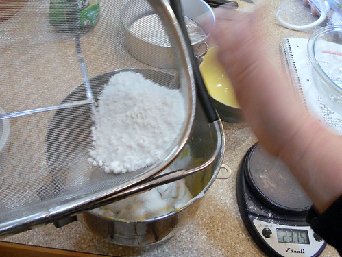 Bringing the three together. Image shows egg whites and yolks in the same bowl and sifting the flour on top.