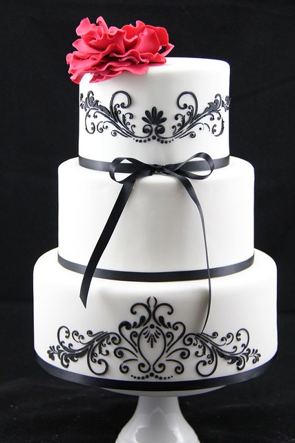 Black on white stencilled filigree wedding cake with a giant red fantasy
