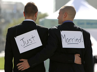two grooms wearing just married signs on their backs
