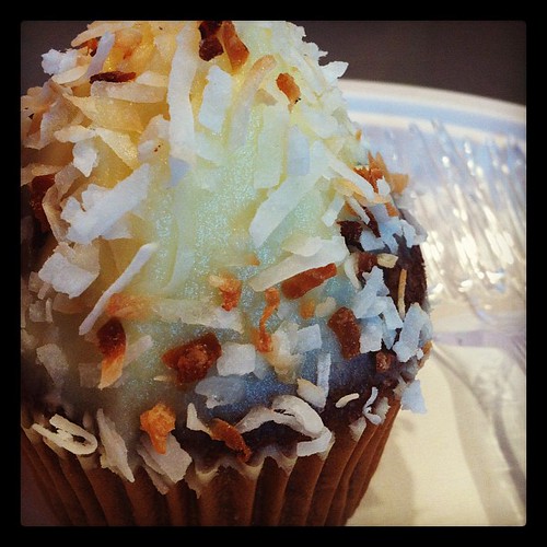 Carrot cake cupcake with cream cheese frosting and toasted coconut.