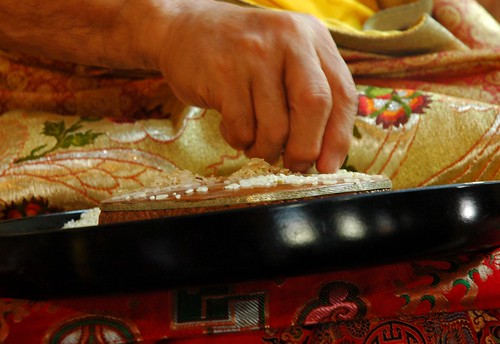 Closeup of the hand of His Holiness Jigdal Dagchen Sakya making a rice visualized mandala offering, mandala plate, rice tray, silks, ritual tradition, Sakya Lamdre, Tharlam Monastery of Tibetan Buddhism, Boudhanath, Kathmandu, Nepal by Wonderlane
