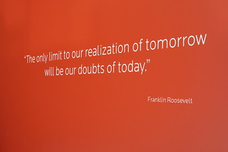 Red image with text "The only limit to our realization of tomorrow will be our doubts of today" by Franklin Roosevelt.