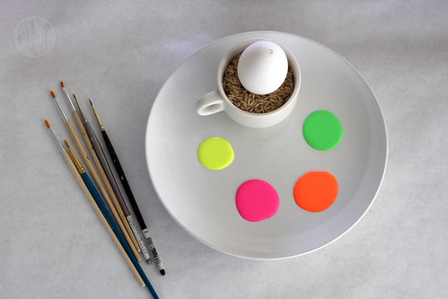 neon paint on a plate with paintbrushes and an egg for painting