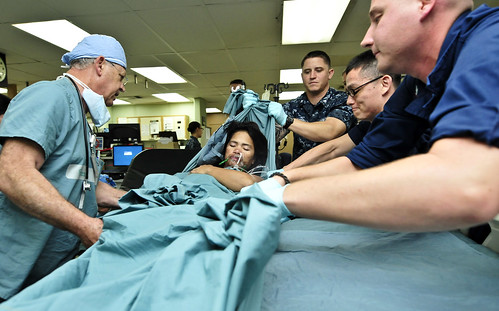 Service members from the U.S. Navy and Australian army help lift a Filipino women onto a bed in the intensive care unit.